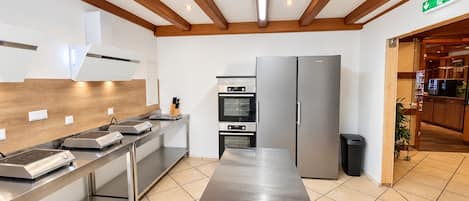 A modern kitchen with stainless steel appliances, wooden beams, and a tiled floor.