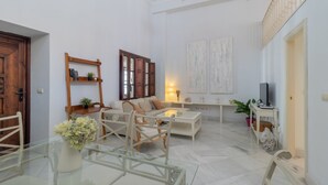 Amplia sala de estar con una mesa de vidrio, un sofá, una mesa de centro y un mueble para la televisión.