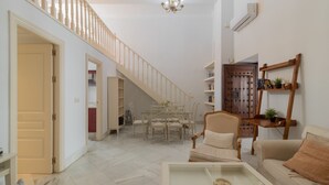 Amplia sala de estar con escalera, mesa de comedor y sofá.
