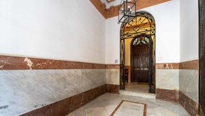 A hallway with marble flooring and a decorative archway leading to a door.