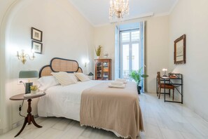 A bedroom with a bed, bedside table, chandelier, and a view of the outside. - La Morada del Pintor (Cordoba)
