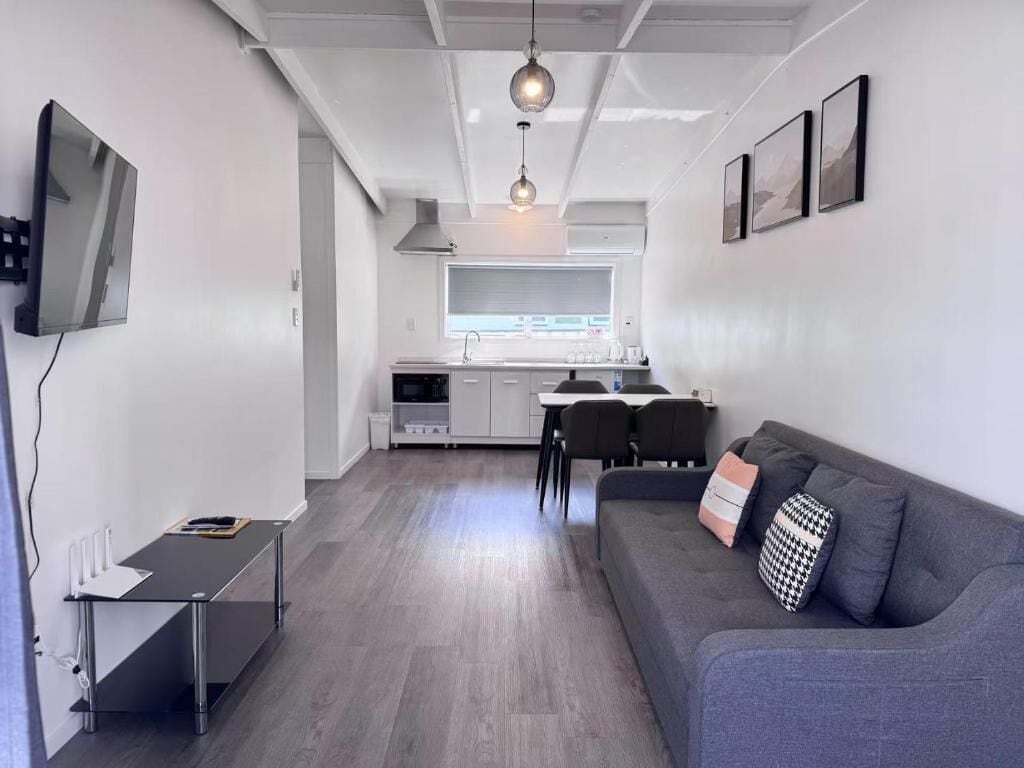 A modern living space with a sofa, a dining table, and a kitchen area.