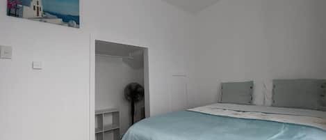 Un dormitorio con una cama, un ventilador y un cuadro en la pared.