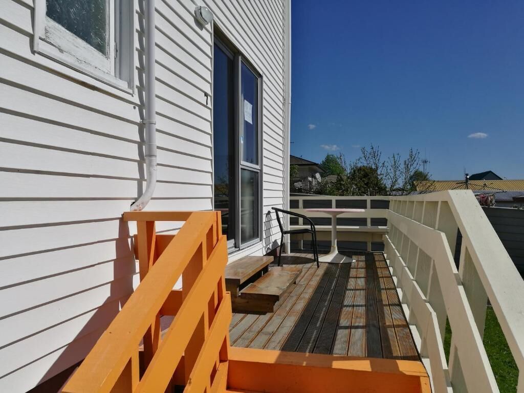 A wooden deck with a white railing, a small table, and a bench.