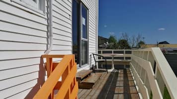 A wooden deck with a white railing, a small table, and a bench.