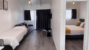 Ett hotellrum med två sängar, en soffa, en TV och ett skrivbord.
