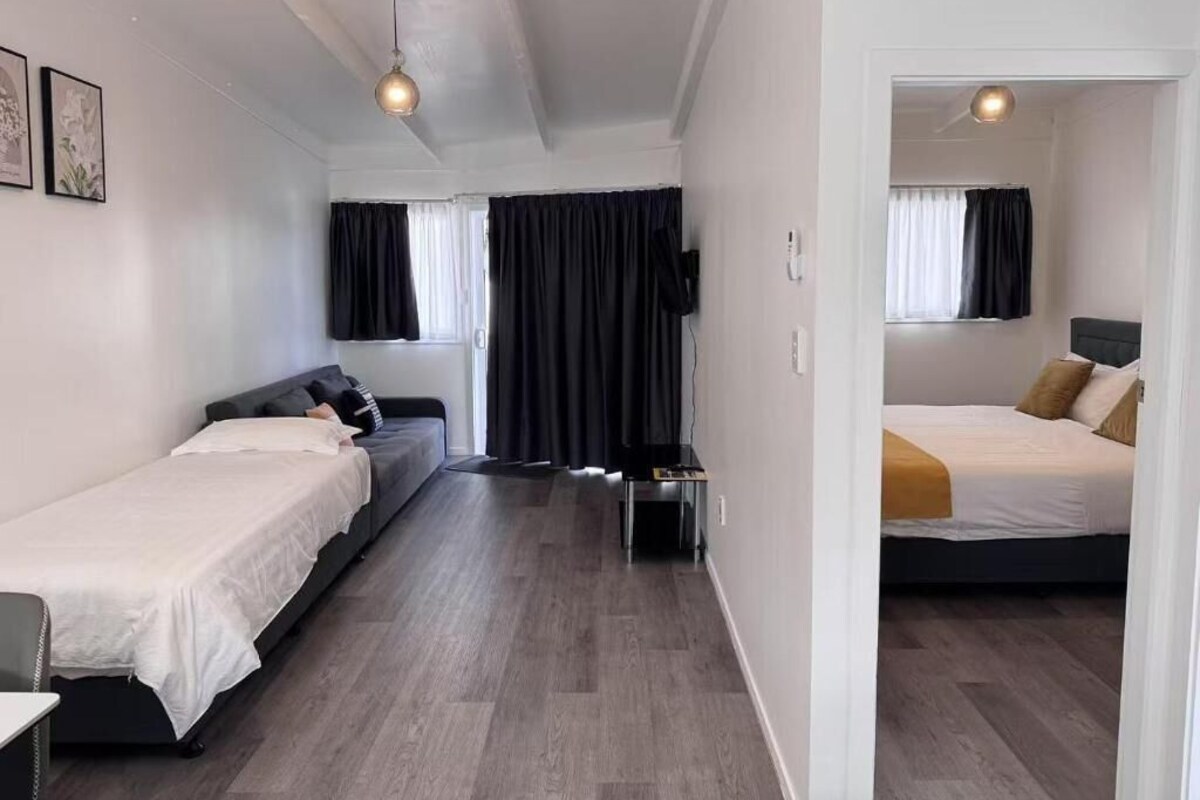 Ett hotellrum med två sängar, en soffa, en TV och ett skrivbord.