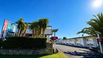 A motel with a signboard, palm trees, and a clear sky.