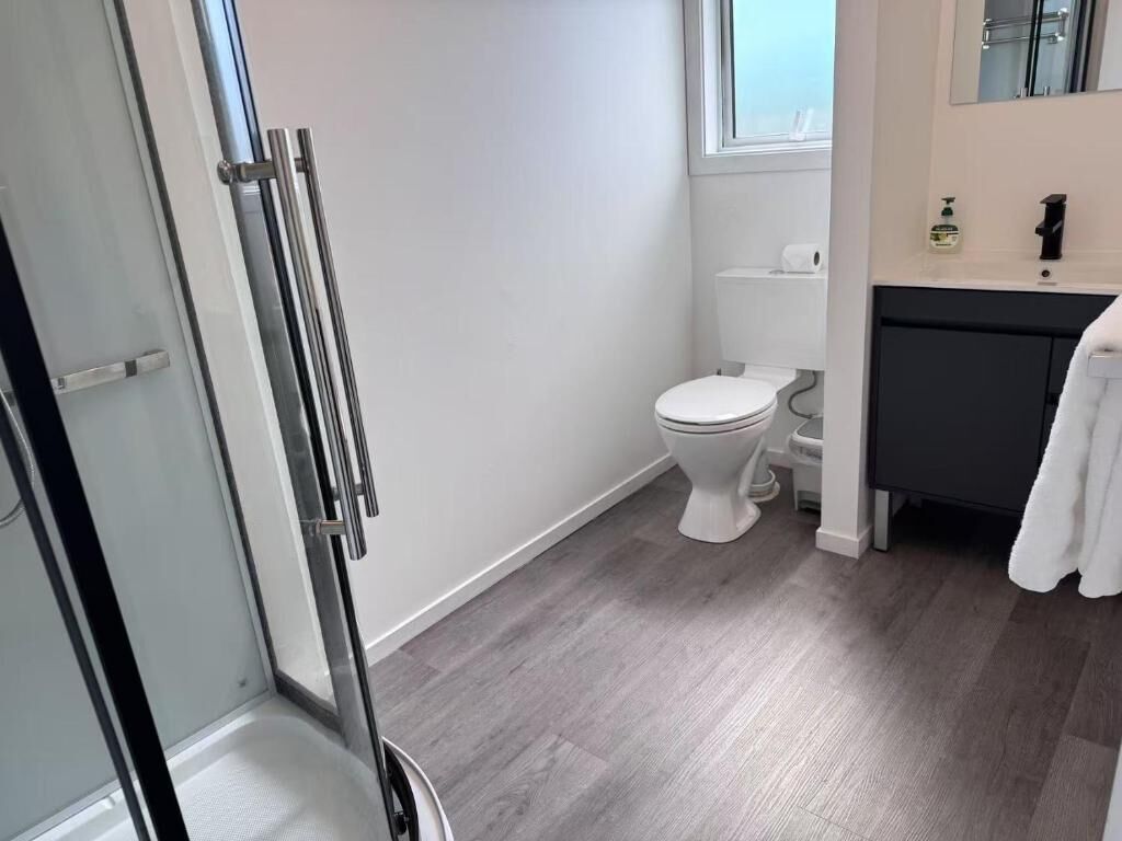 A modern bathroom with a toilet, a shower area, and a sink.