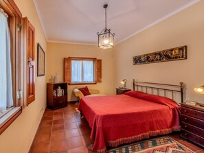 Cozy retreat with a large bed, nightstand, dresser, and window with shutters.