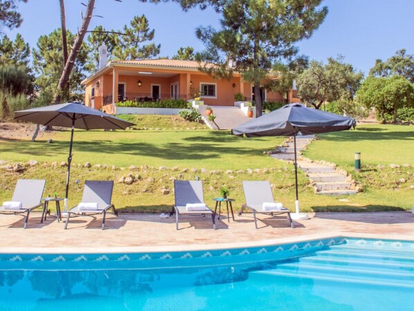 Relax by the serene pool surrounded by lush greenery and comfortable lounge chairs.