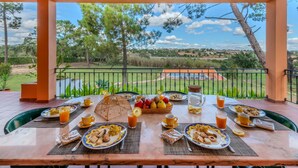 A breakfast table set on a patio with a view of a golf course and trees.