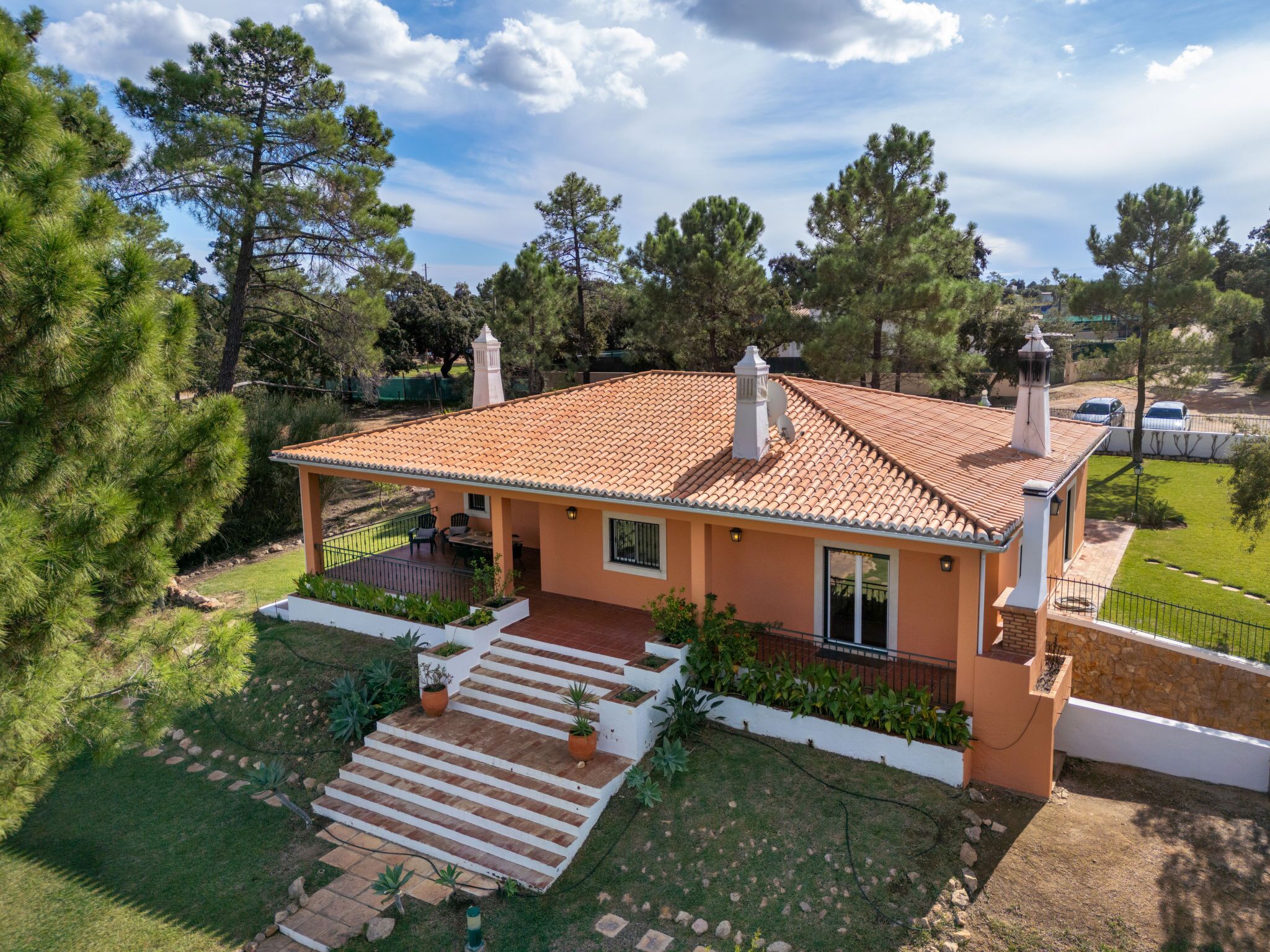 A two-story house with a tiled roof, a covered patio, and a small garden.
