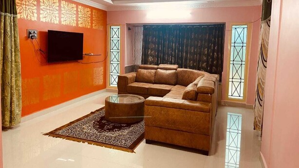 Ein Wohnzimmer mit einer Couch, einem Couchtisch und einem an der Wand montierten Fernseher.