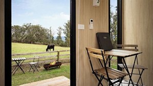 Une pièce avec vue sur un espace verdoyant et une vache, une table en bois et une chaise pliante.