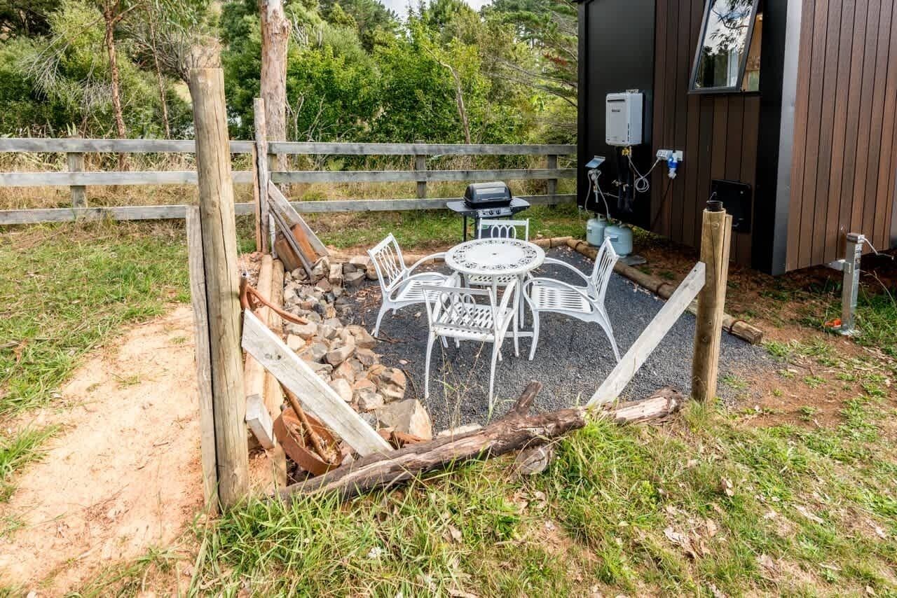 An outdoor seating area with a table and chairs, a grill, and a wooden fence.