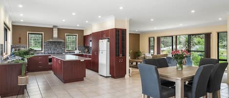 Una cocina moderna con armarios de madera oscura, una isla central y un comedor con mesa y sillas.