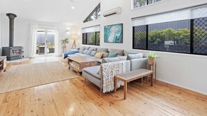 Ein modernes Wohnzimmer mit einer Sofagarnitur, Holzböden und großen Fenstern.
