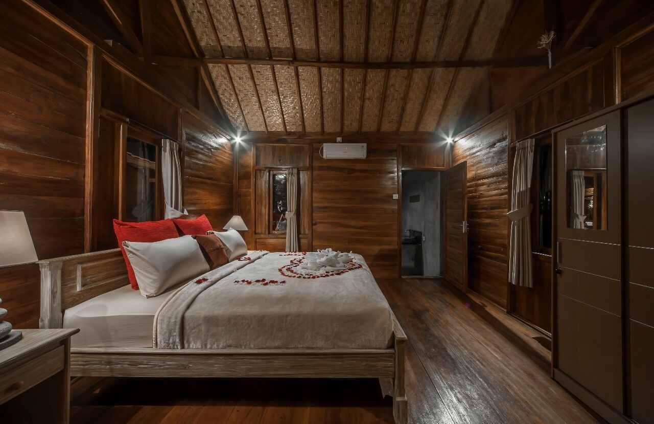 A wooden room with a bed, a nightstand, and a wardrobe.