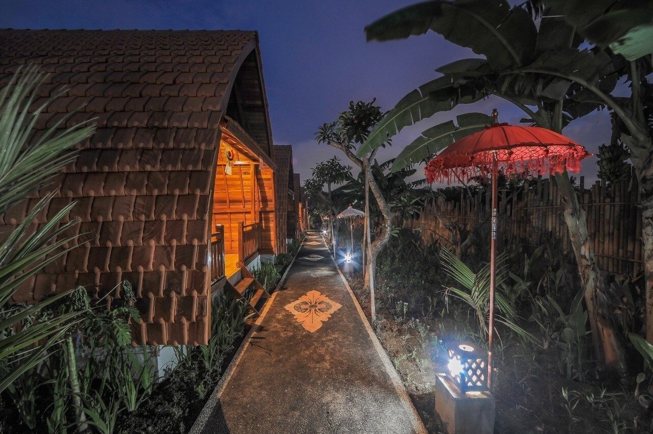 A pathway leading to a building with a tiled roof and a red umbrella.