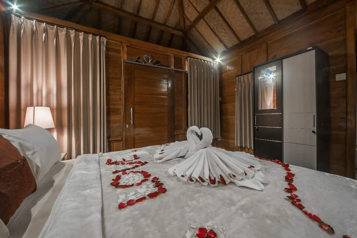 Une chambre d’hôtel avec un lit, des rideaux, une armoire et une lampe.