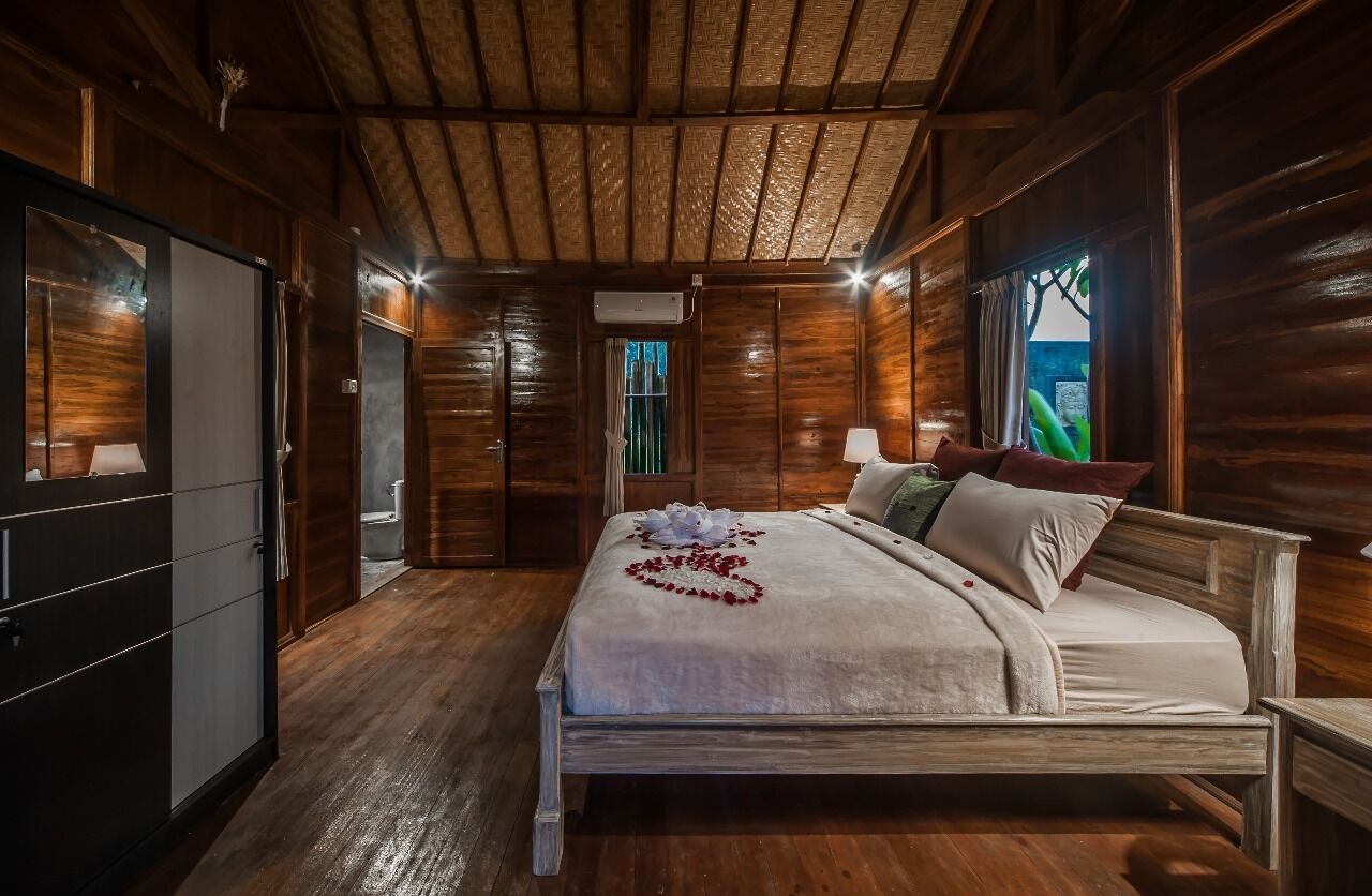 A wooden cabin-style bedroom with a bed, bedside table, and a wardrobe.