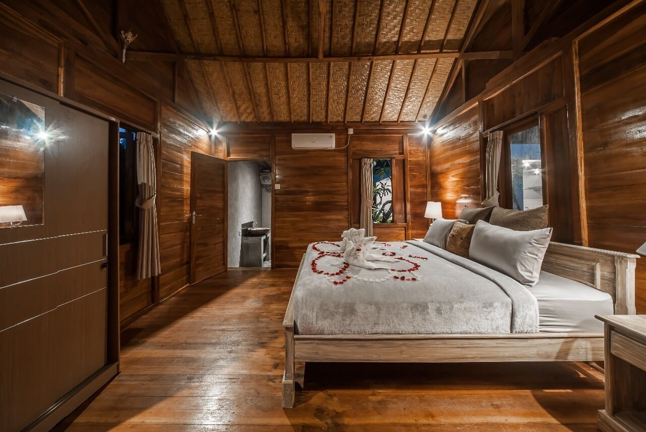 A wooden cabin bedroom with a bed, a nightstand, and a window.