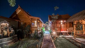 A pathway leading to wooden buildings with traditional architecture, surrounded by tropical plants. - The Lebak Canggu (Canggu)