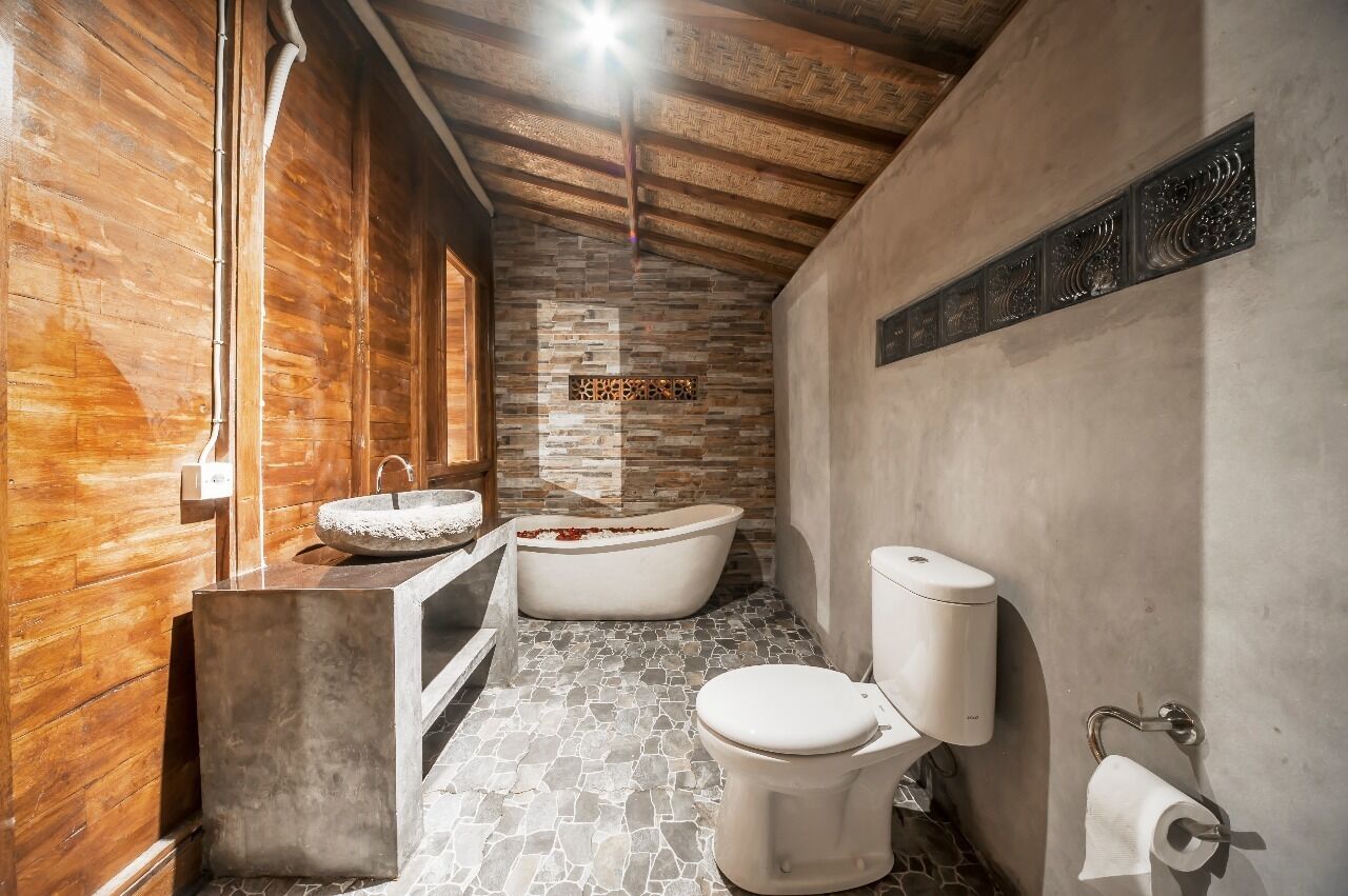 A bathroom with a stone floor, a freestanding bathtub, a sink, and a toilet.