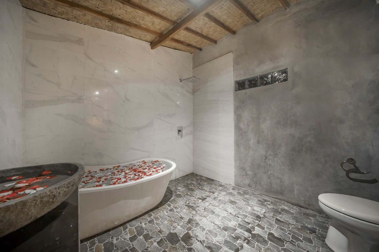 Un baño con bañera independiente, inodoro y zona de ducha.