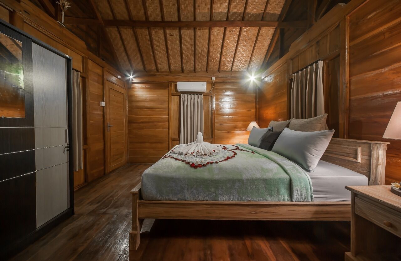 A wooden cabin-style bedroom with a bed, bedside tables, and a wardrobe.