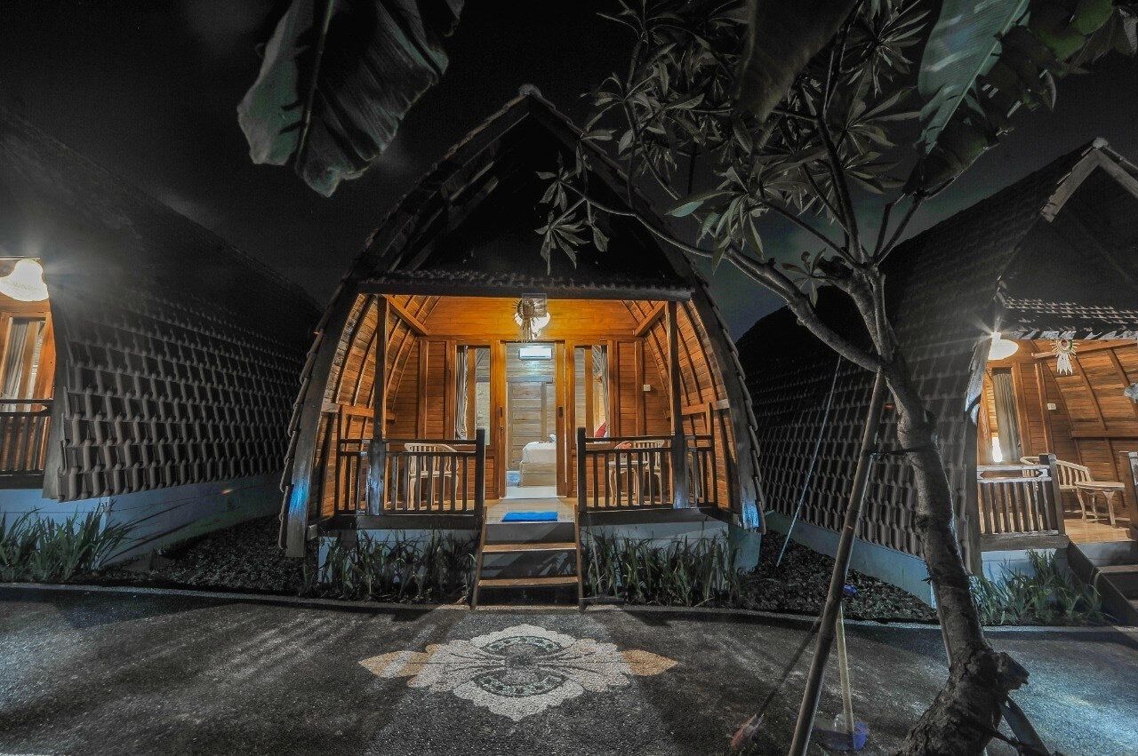 Uma cabana de madeira acolhedora e bem iluminada, com porta central e um pequeno alpendre.