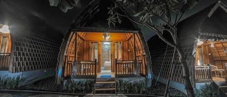 Uma cabana de madeira acolhedora e bem iluminada, com porta central e um pequeno alpendre.
