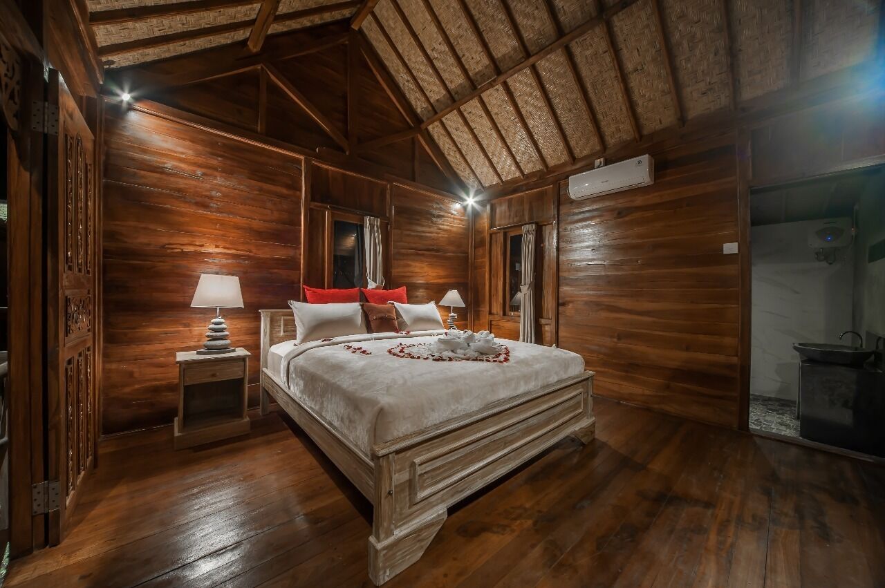 Ein Zimmer mit Holzboden, einem Bett, zwei Nachttischen und einer Decke mit freiliegenden Balken.