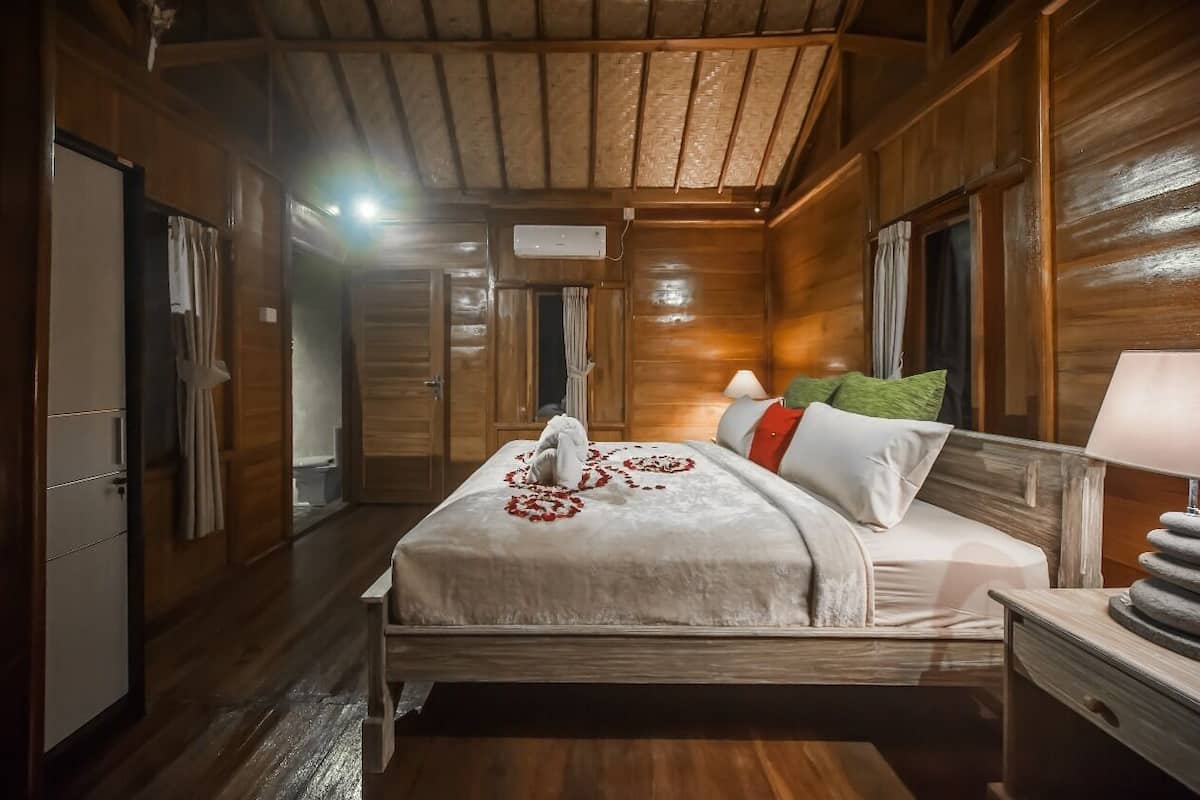 Une chambre rustique en bois, avec un lit, une table de chevet, une lampe et une fenêtre.