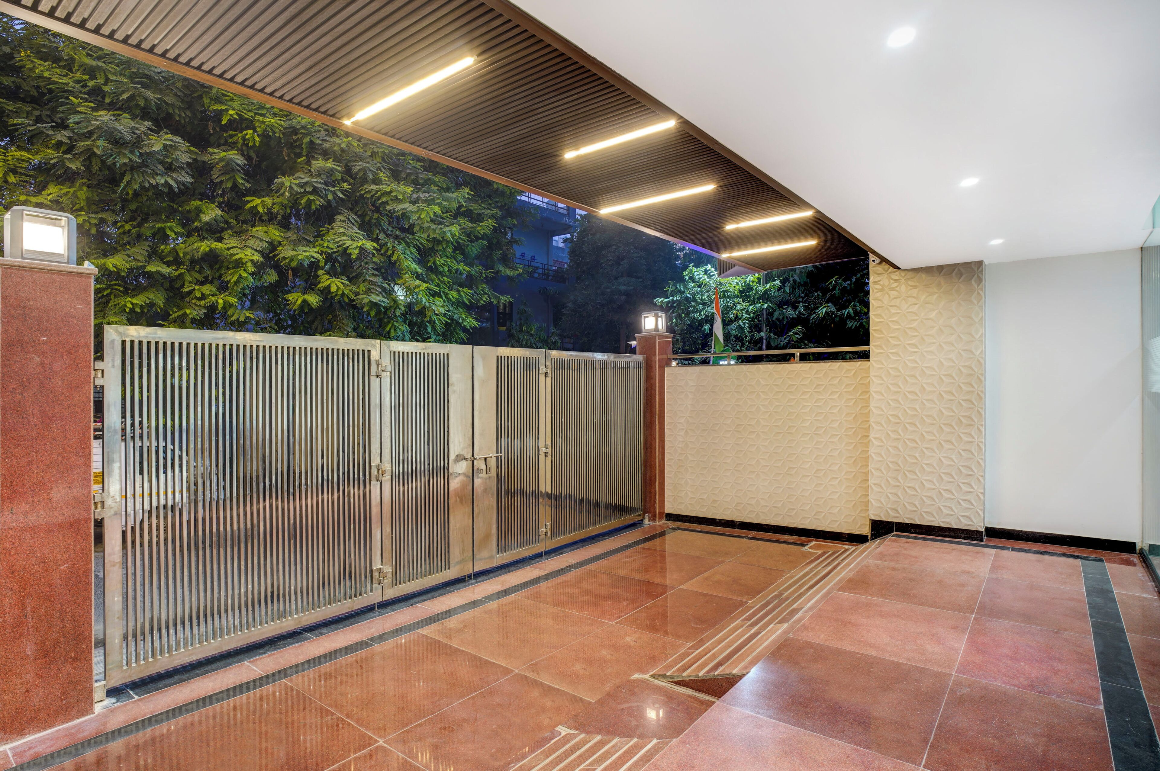 A modern indoor space with a metal gate, tiled flooring, and a wall with a geometric pattern.