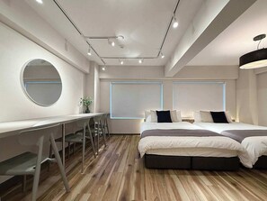 A modern bedroom with a desk, two beds, and a large mirror.