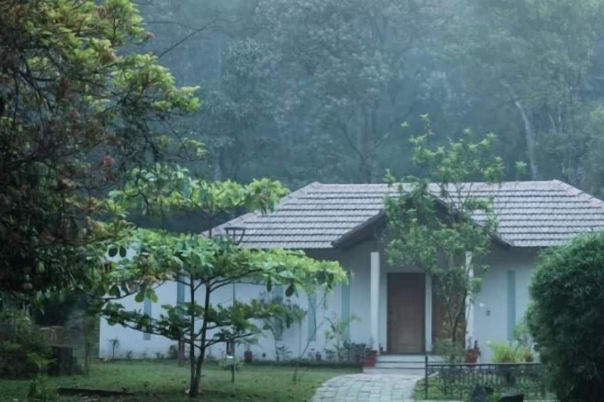 A single-story building with a tiled roof, surrounded by lush greenery and trees.