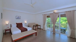 A hotel room with a bed, a bench, a small table with a flower, a ceiling fan, and a balcony with curtains. - Abad Brookside (Vythiri)