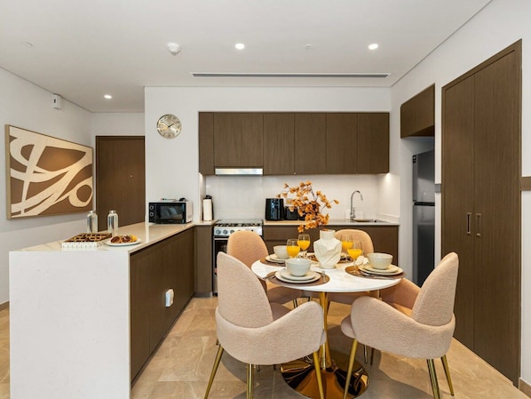 A modern kitchen with a central island, two chairs, and a dining table set for four.