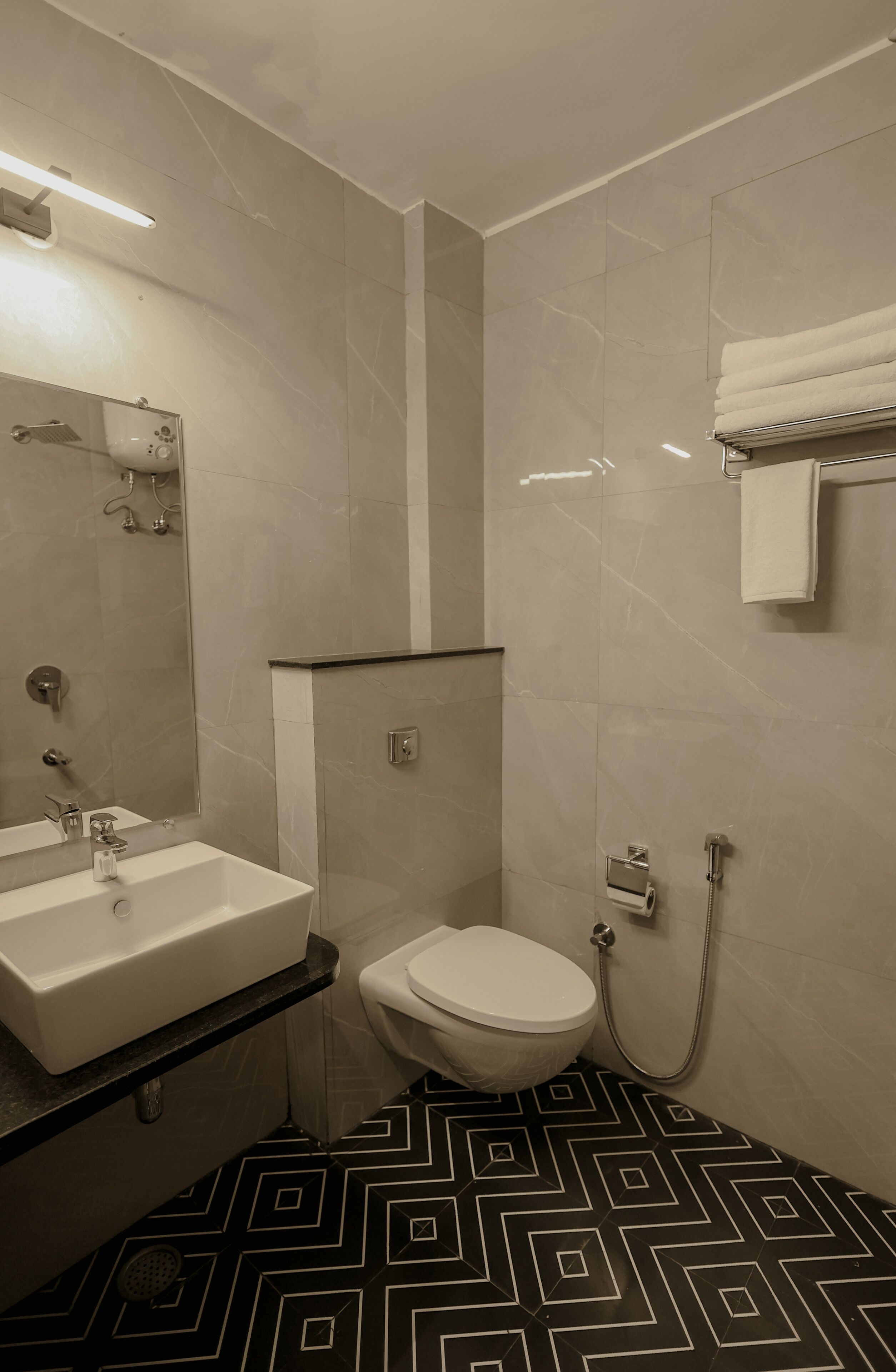 A bathroom with a white sink, toilet, and shower. The floor has a black and white geometric pattern.