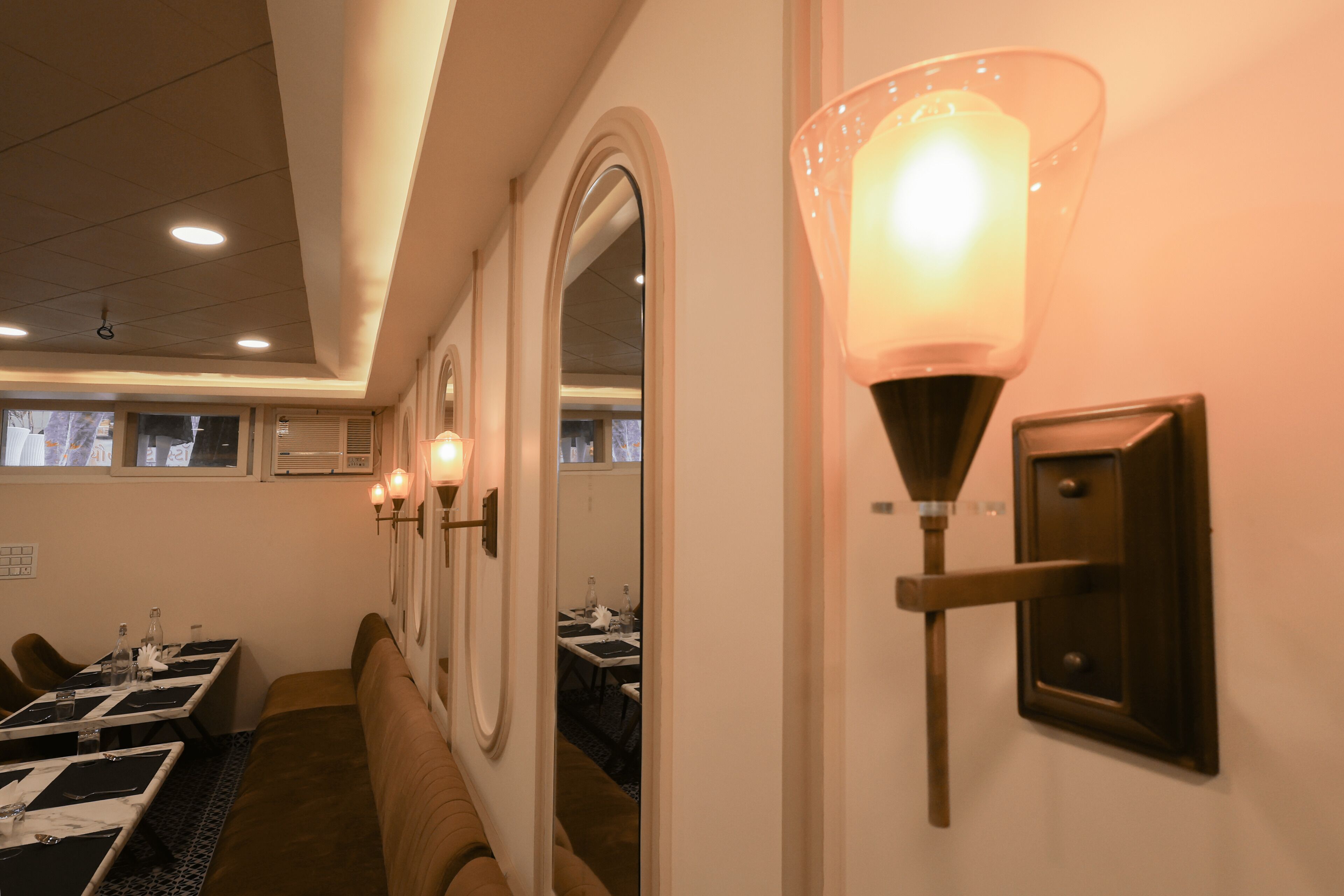 A hotel room with a dining area, a bench, and a wall-mounted light fixture.