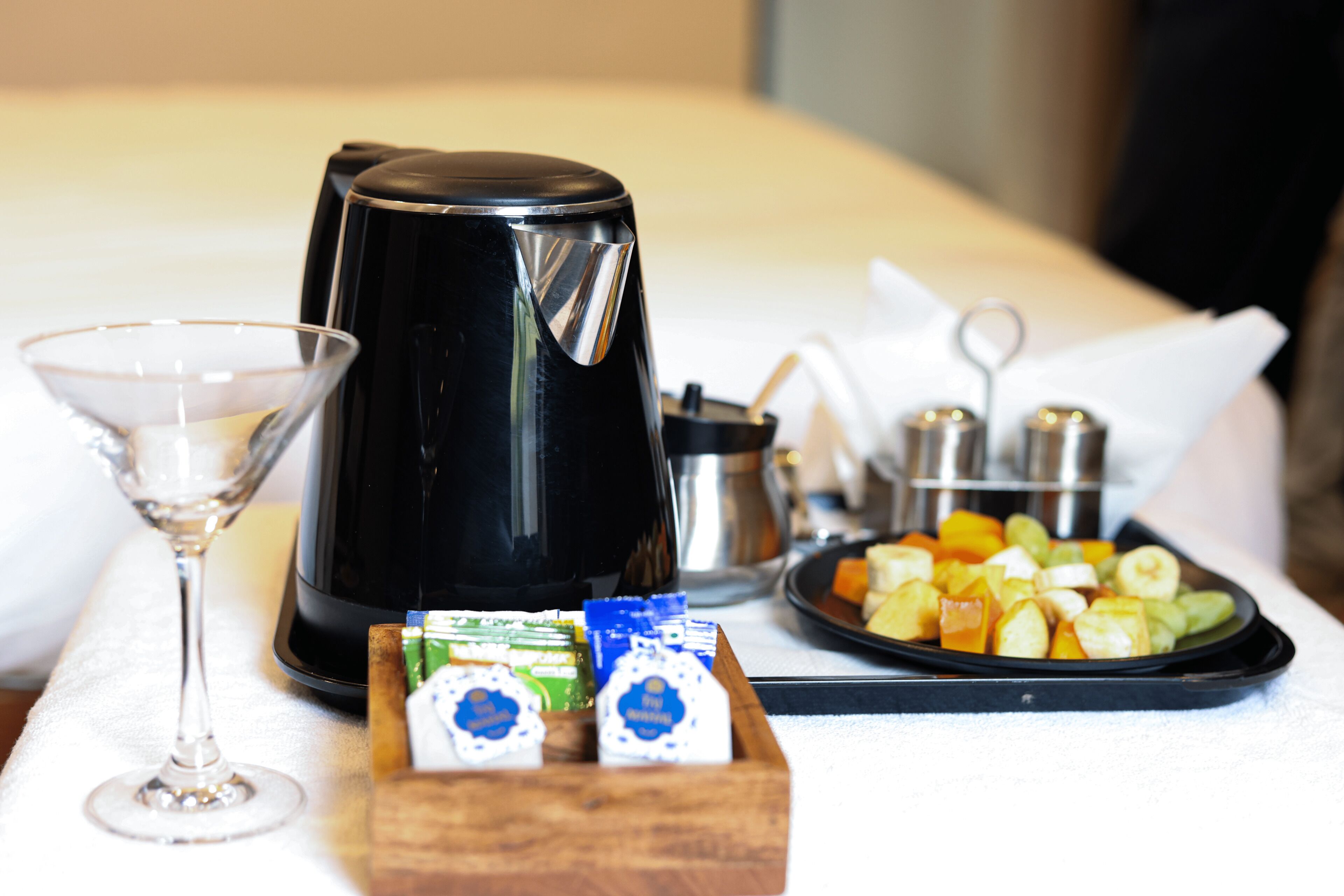 A tray with a coffee maker, a martini glass, and a plate of fruit.