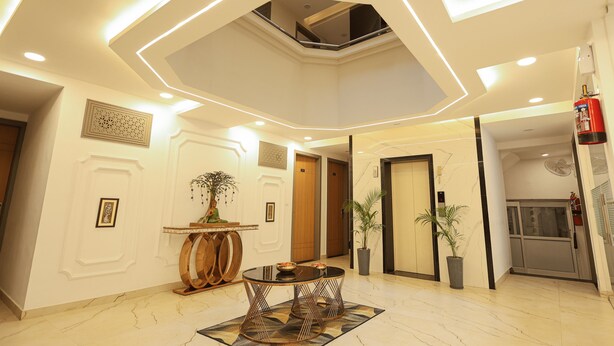 A modern lobby with a central round table, a ceiling with recessed lighting, and a fire extinguisher on the wall. - Arjun - A boutique hotel (Haridwar)