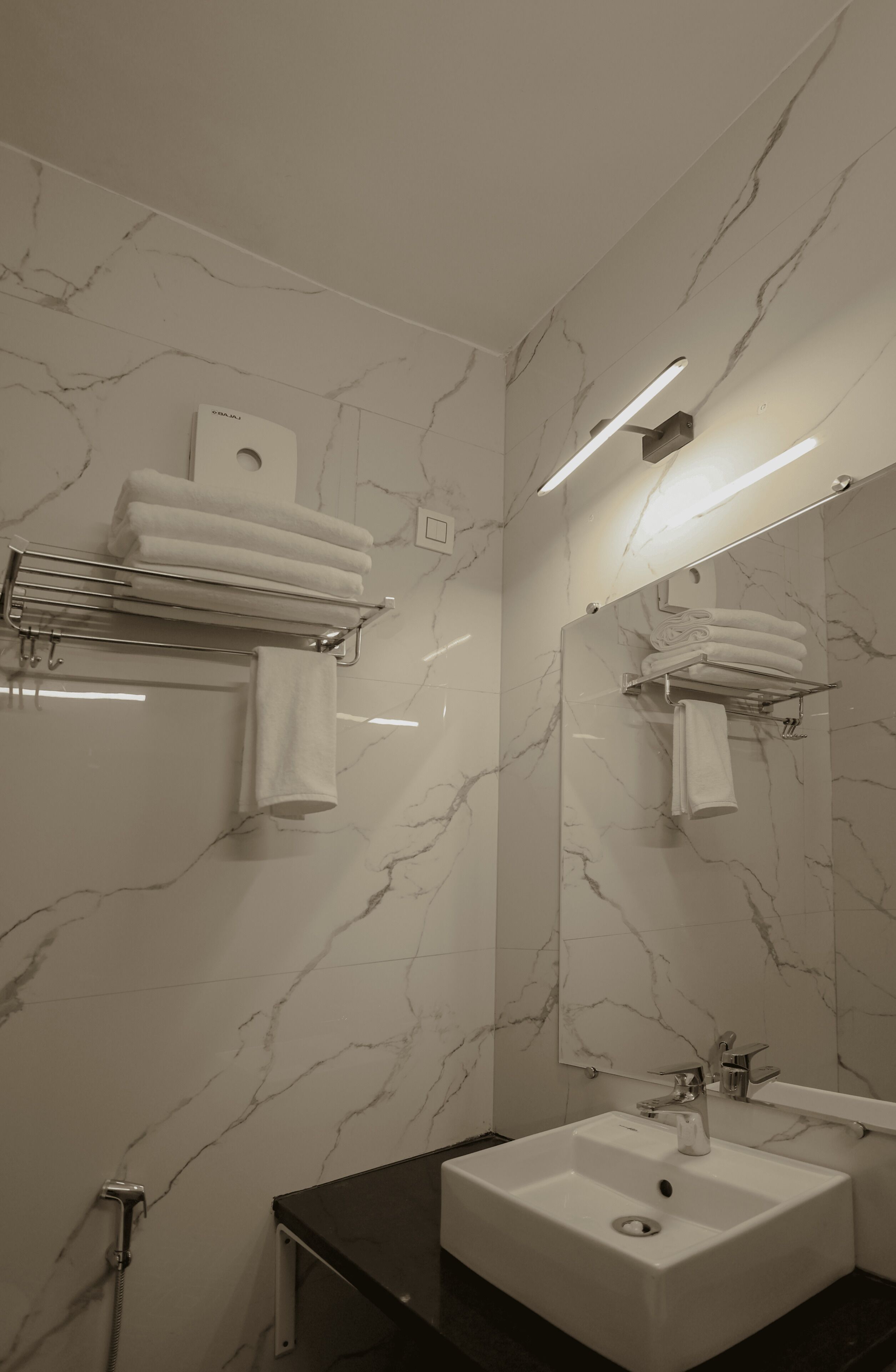 Een badkamer met marmeren wanden, een wit wastafelmeubel en een handdoekhouder.