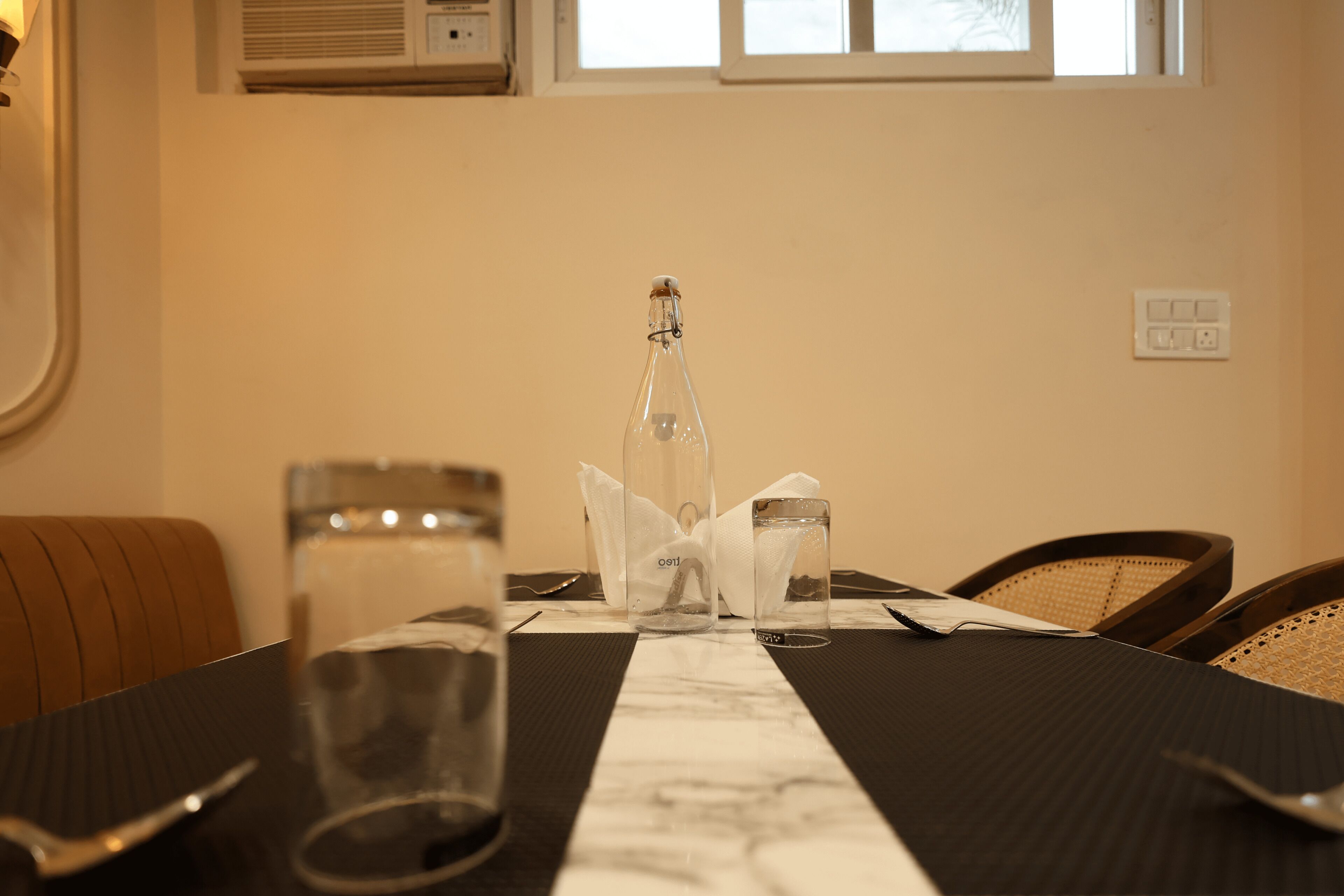 Une table à manger avec une bouteille, des verres et une serviette.