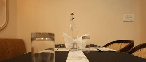 Une table à manger avec une bouteille, des verres et une serviette.