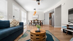 A modern living room with a sofa, coffee table, dining table, and kitchen area. - Del Boca Vista|Pool, Screened Porch, 5 to Beach (Largo)