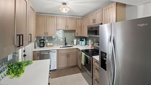 A modern kitchen with wooden cabinets, stainless steel appliances, and a tiled backsplash. - Del Boca Vista|Pool, Screened Porch, 5 to Beach (Largo)