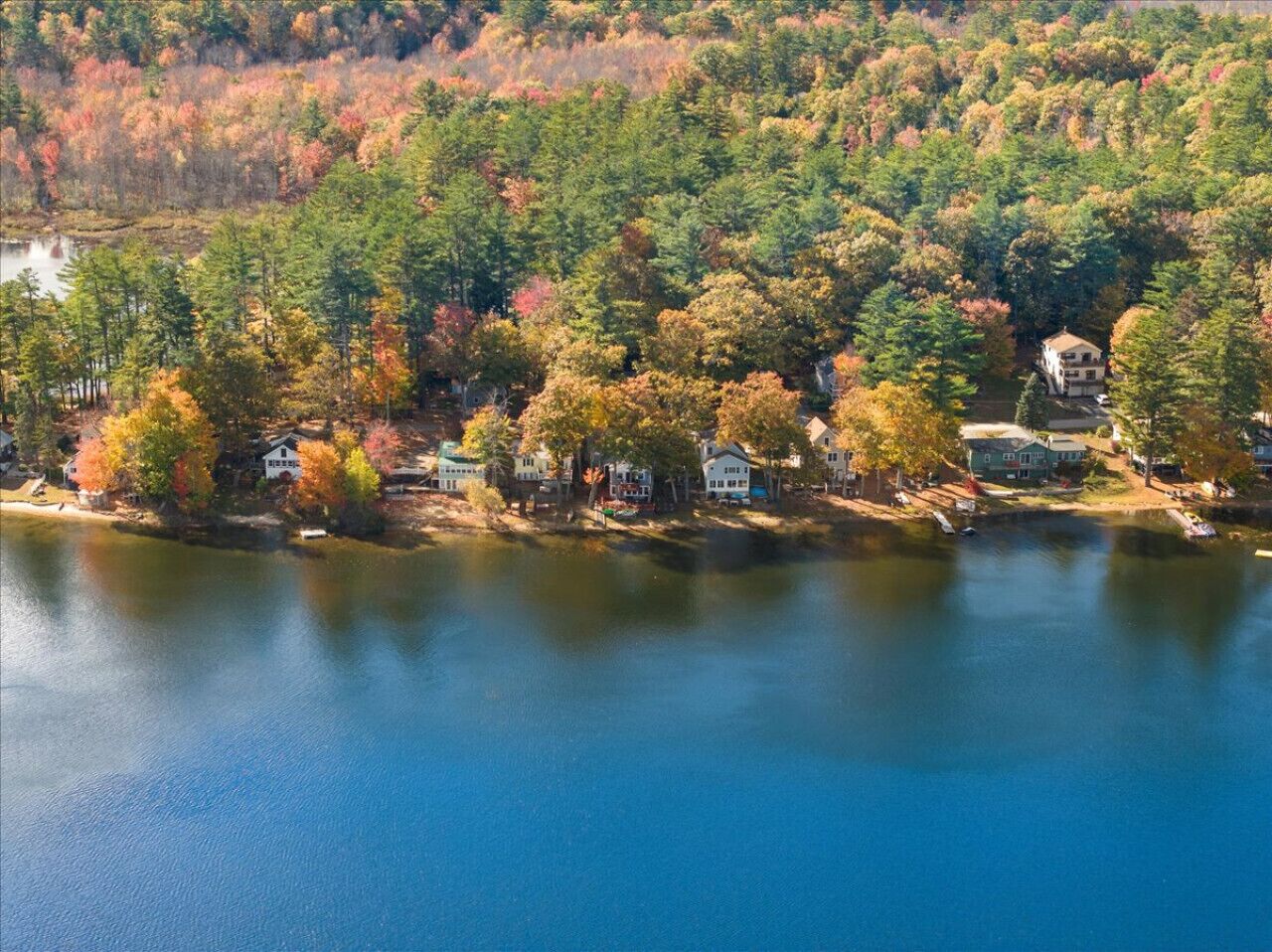 A lakeside property with multiple houses, a dock, and a forested backdrop.